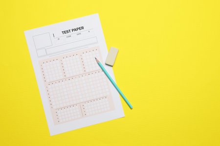 Student passing exam. Answer sheet, pencil and eraser on yellow background, flat lay. Space for textの写真素材