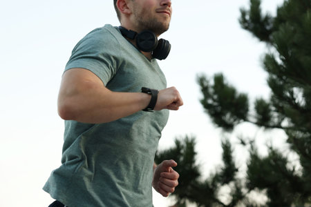 Athletic young man in sportswear running outdoors, closeup