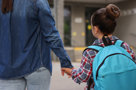 Mother taking her daughter to school outdoors, back viewの写真素材