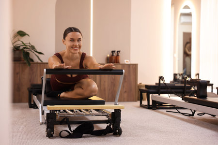 Woman exercising on reformer in pilates studio, space for textの写真素材