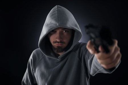 Criminal with gun on dark background, selective focusの写真素材