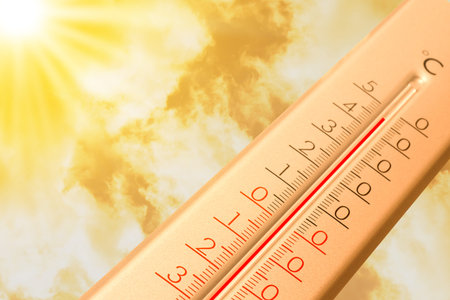 Extremely high temperature on thermometer against orange sky on sunny day. Severely hot summer...