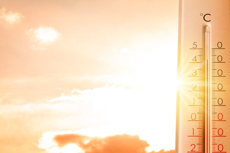 High temperature on thermometer against orange sky on sunny day. Hot summer weatherの写真素材