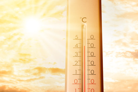 High temperature on thermometer against orange sky on sunny day. Hot summer weatherの写真素材