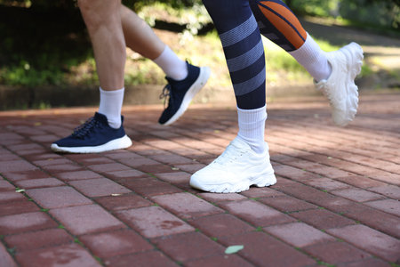 Young woman running with professional personal trainer outdoors, closeup
