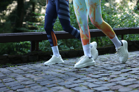 Young woman running with professional personal trainer outdoors, closeup