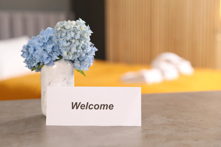 Card with word Welcome and hydrangea flowers on grey table indoorsの写真素材