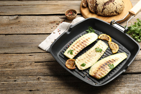 Delicious grilled courgette slices with spices and lemon in pan on wooden table, closeupの写真素材