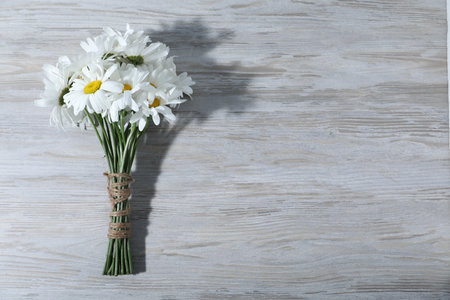 Bouquet of beautiful chamomile flowers on grey wooden table, top view. Space for textの写真素材