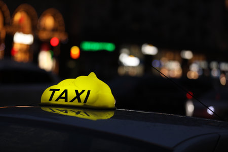 Taxi car with yellow checkered sign on city street in evening, closeupの写真素材