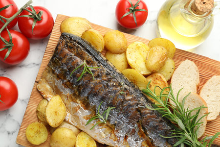 Tasty roasted mackerel with spices and vegetables on white marble table, flat lay. Homemade seafood dishの写真素材