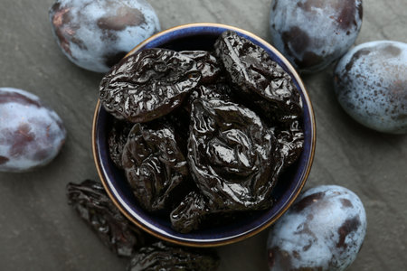 Dried prunes and fresh plums on black table, flat layの写真素材
