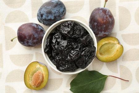Dried prunes, fresh plums and green leaf on table, flat layの写真素材