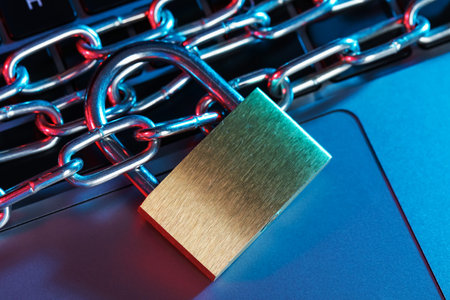 Cyber safety. Metal padlock with chain on laptop in color lights, top view