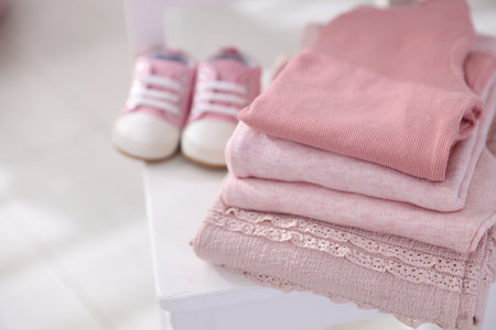 Stack of clean baby clothes and shoes on small chair indoors, closeup. Space for textの写真素材