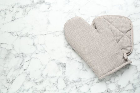 Oven glove and potholder on white marble table, flat lay. Space for textの写真素材