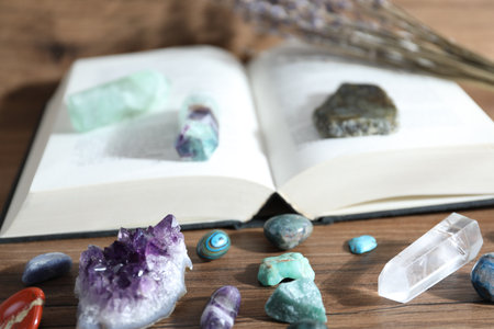 Different healing stones and book on wooden table, closeupの写真素材
