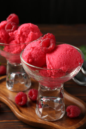 Delicious raspberry sorbet in dessert bowls and fresh berries on wooden table against black background, closeupの写真素材