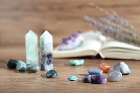 Different healing stones and book on wooden table, closeupの写真素材
