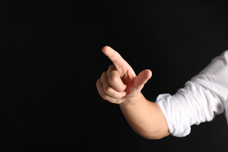 Man touching something on black background, closeup. Space for textの写真素材