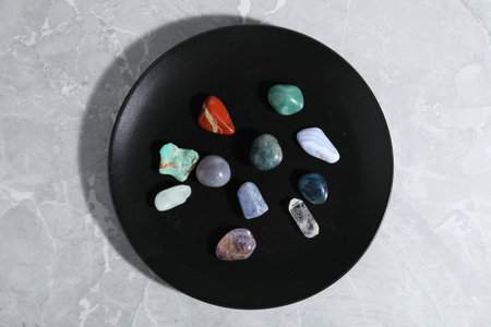 Many different healing stones on light grey table, top view