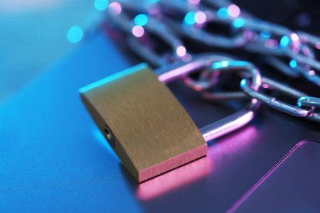 Cyber safety. Metal padlock with chain on laptop, closeupの写真素材