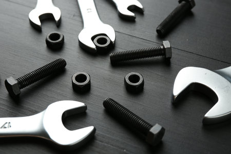 Many metal wrenches, bolts and nuts on black wooden table, closeupの写真素材