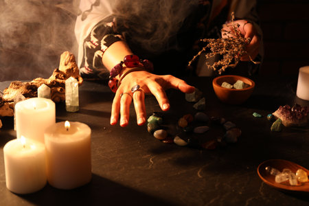 Woman doing ritual with healing stones at dark table, closeupの写真素材