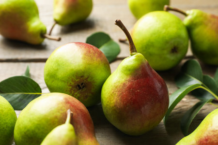Fresh ripe pears and green leaves on wooden table, closeupの写真素材