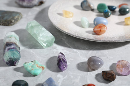 Many different healing stones on light grey table, closeup
