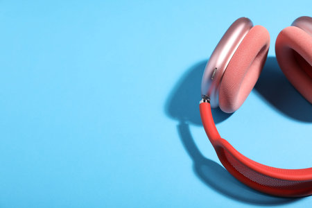 Pair of stylish pink headphones on light blue background, above view. Space for textの写真素材