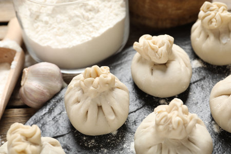 Uncooked khinkalis (dumplings), flour and garlic on table, closeupの写真素材
