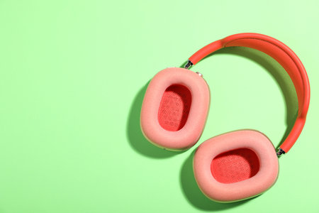 Pair of stylish pink headphones on light green background, top view. Space for textの写真素材