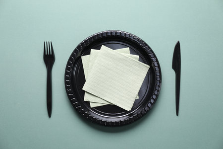 Set of disposable plastic tableware and paper napkins on grey background, flat layの写真素材