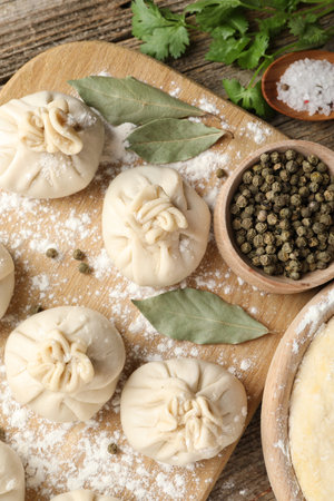 Uncooked khinkalis (dumplings) with peppercorns, flour, parsley and bay leaves on wooden table, flat layの写真素材