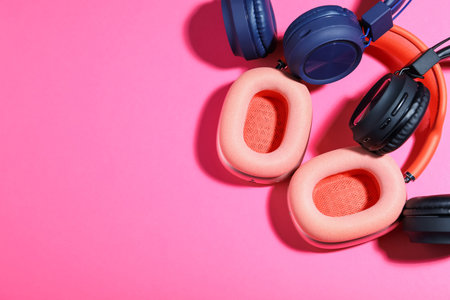 Different stylish headphones on pink background, flat lay. Space for textの写真素材