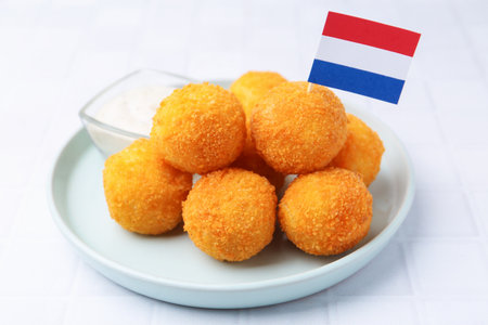 Delicious fried croquette balls and flag of Netherlands on light tiled table, closeupの写真素材