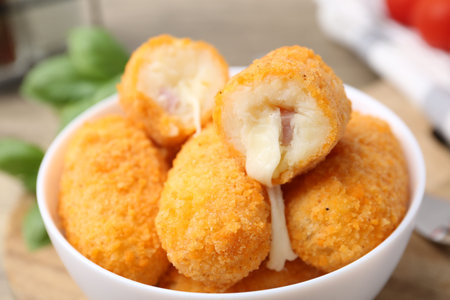 Delicious fried croquettes in bowl on table, closeup