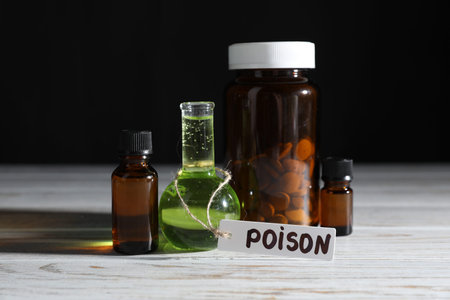 Bottles with poisons on wooden table against black background