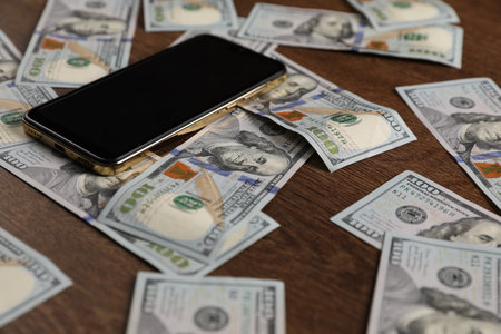 Smartphone and dollars on wooden table, closeupの写真素材