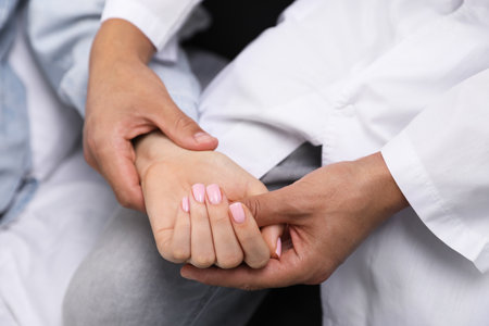 Doctor checking woman's pulse with fingers at home, closeupの写真素材