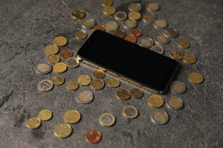 Smartphone and coins on grey table, closeupの写真素材