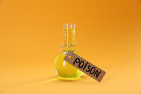 Glass flask with poison on orange background, closeupの写真素材