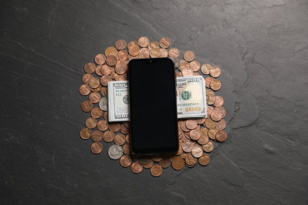 Smartphone, dollars and coins on black table, flat layの写真素材