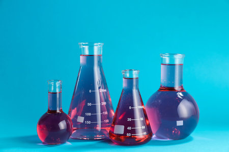 Laboratory glassware with color liquid on light blue backgroundの写真素材