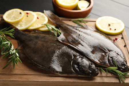 Fresh raw flounder fish and spices on black wooden table, closeup. Seafoodの写真素材