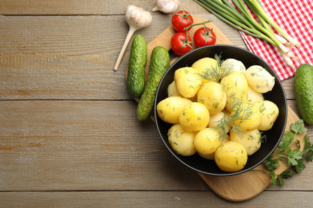 Tasty young boiled potatoes with dill in bowl and products on wooden table, flat lay. Space for textの写真素材