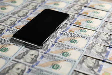 Smartphone on dollar banknotes as background, closeupの写真素材