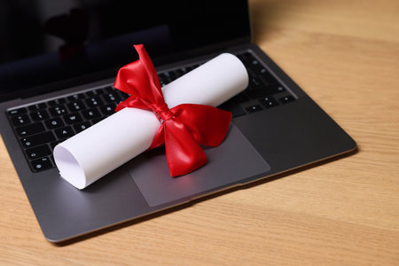 Diploma and laptop on wooden table, closeupの写真素材