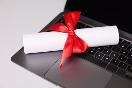 Diploma and laptop on light table, closeupの写真素材